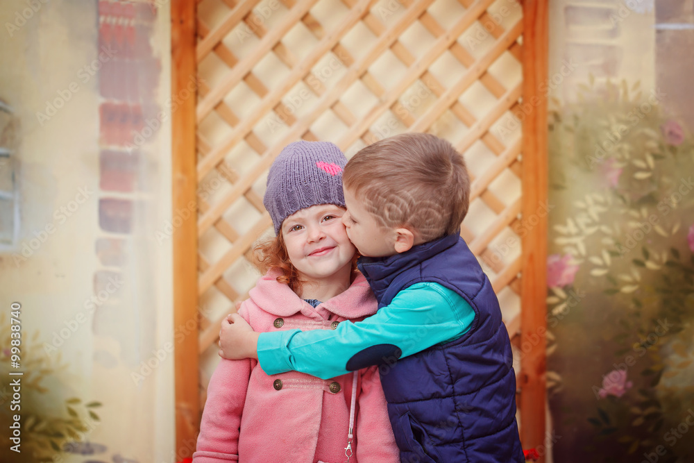 Little boy kissing smiling little girl on her cheek, outdoor por Stock