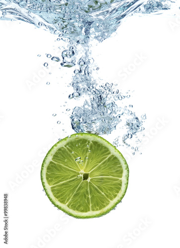 Lime dropped in a water above white background