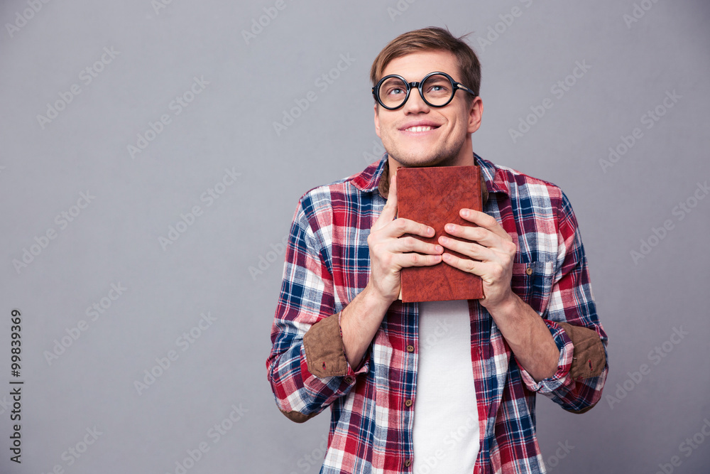 Funny cheerful young man in round glasses holding book Funny cheerful young man in round glasses holding book