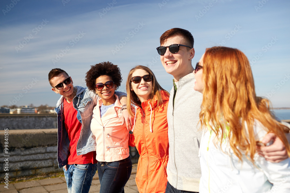 happy teenage friends walking along city street happy teenage friends walking along city street