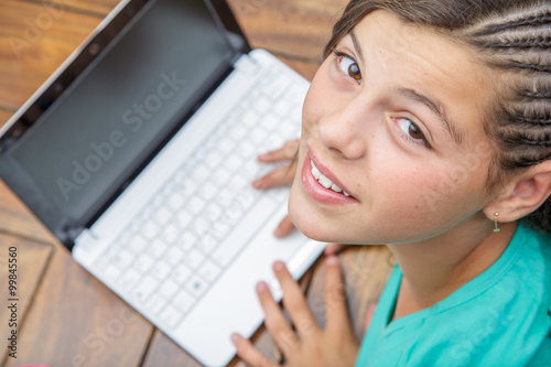 closeup of pretty young girl smiling who types on a computer keyboard seen from above