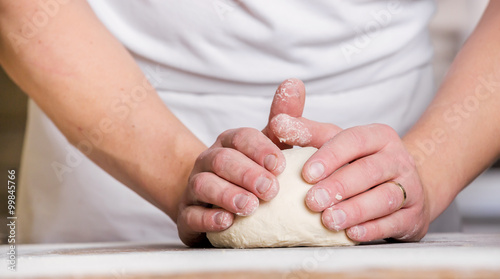 Fotografie Close-up the hand of a baker kneading and shaping dough