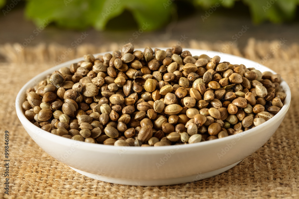 A white ceramic bowl full of hemp seeds, close up A white ceramic bowl full of hemp seeds, close up