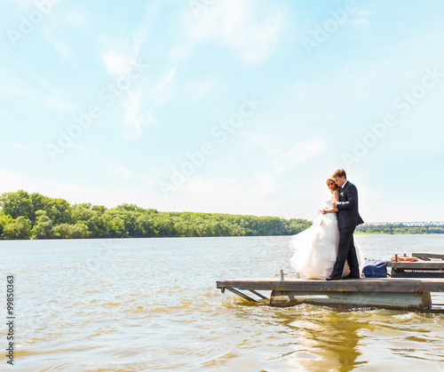 loving wedding couple embarcing near water