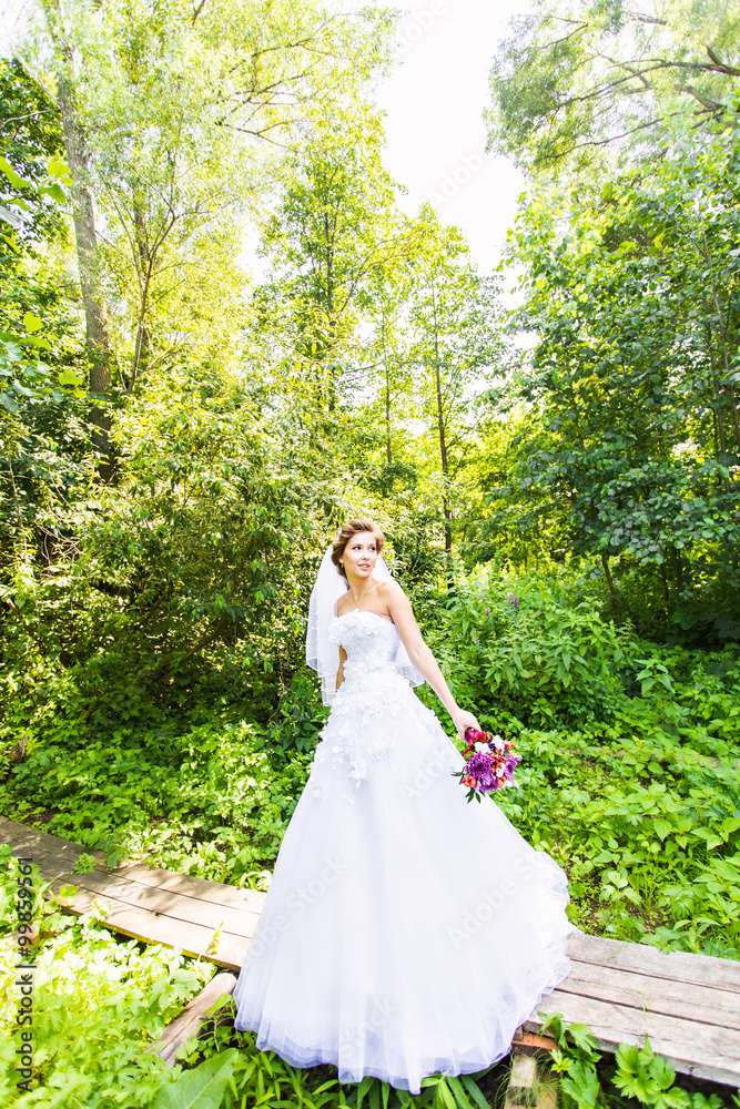 Beautiful bride outdoors with wedding bouquet