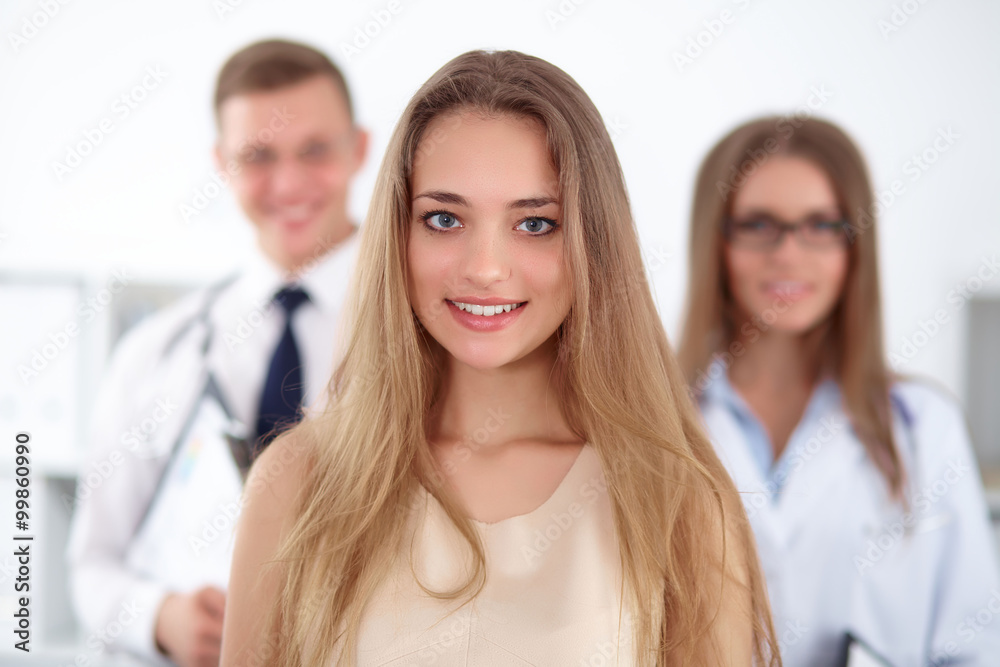 Happy smiling female patient with two cheerful doctors in the background. Medical and health care concept Happy smiling female patient with two cheerful doctors in the background. Medical and health care concept
