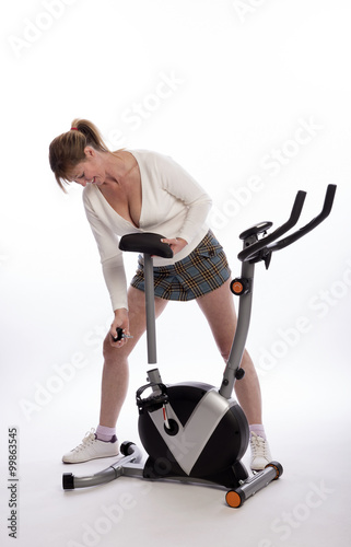 Woman adjusting the height of the saddle on an exercise bike