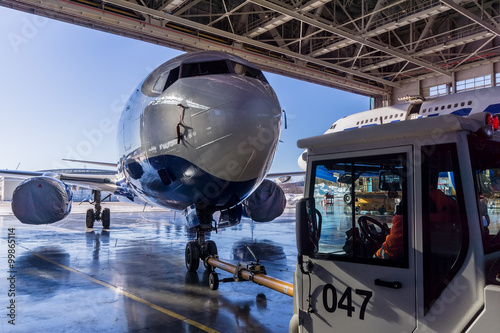 Obraz na plátně TUG Pushback tractor carries a passenger jet in hangar.