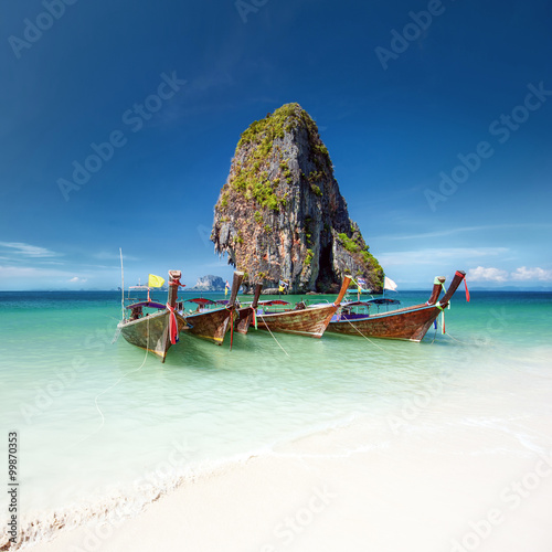 Travel photography of wooden boats on shore of tropical sea with scenic rock mountain in water. Vacation journey background of Thailand nature