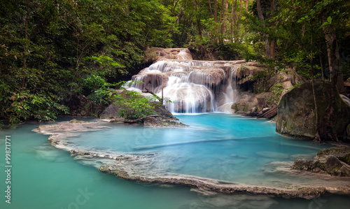 Mountain river stream flows through tropical forest and falls from cascades and waterfalls in wild lake with blue water