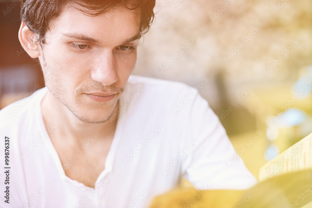 Fototapeta premium Young man reading a brochure. Toning, instagram effect. Blurred background. Looking at his side.