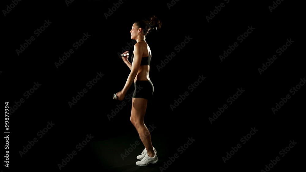 Woman wearing sporstwear is exercising jumping with weights slow motion Woman wearing sporstwear is exercising jumping with weights slow motion