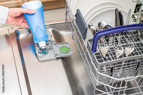 Man poures a Rinse Aid into the dishwasher