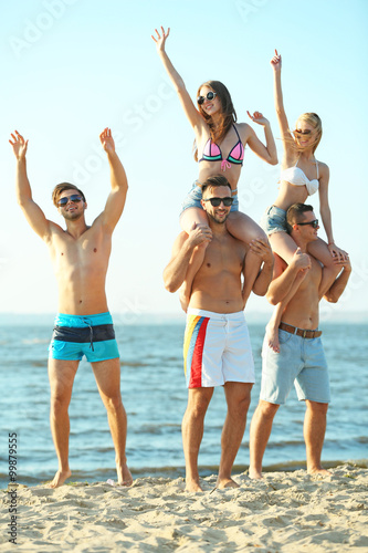 Guys carrying girls on the shoulders, at the beach, outdoors