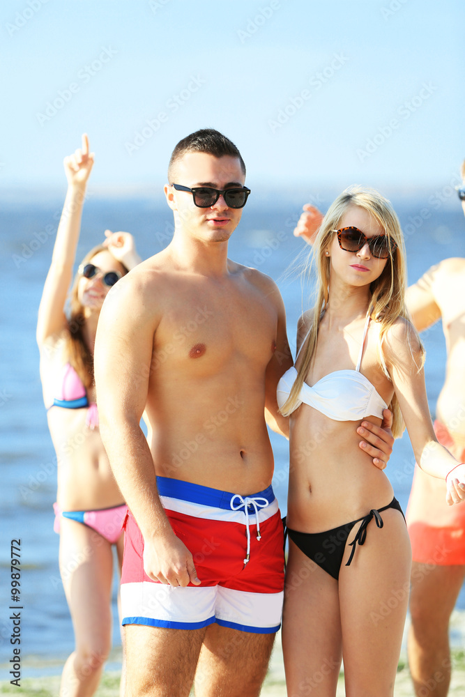 Happy couple and their playful friends relaxing at the beach, outdoors Happy couple and their playful friends relaxing at the beach, outdoors