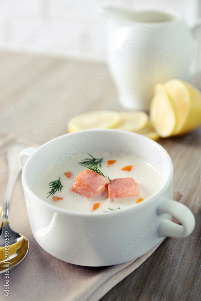 Delicious salmon cream soup on wooden table, which served with sliced lemon and spices Delicious salmon cream soup on wooden table, which served with sliced lemon and spices