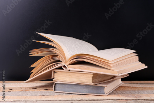 Stack of books on wooden table, black background
