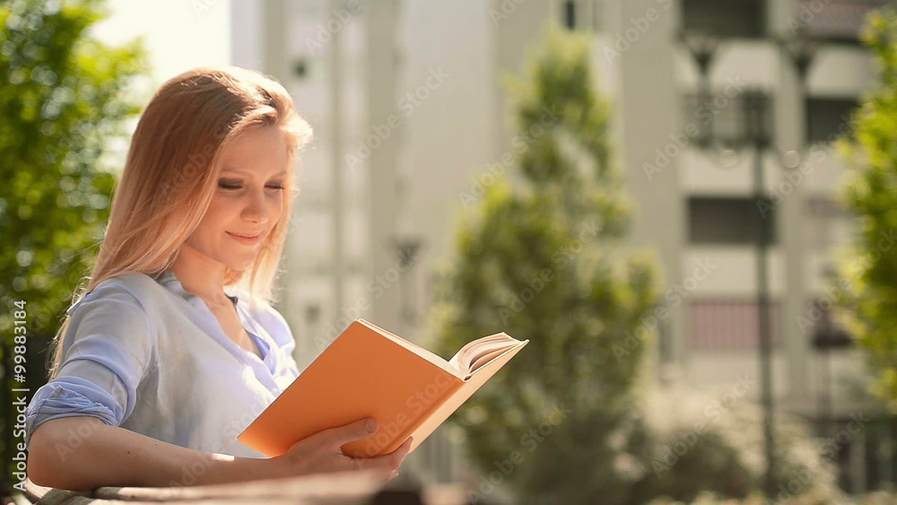 Young blonde woman reading book on bench at park Young blonde woman reading book on bench at park