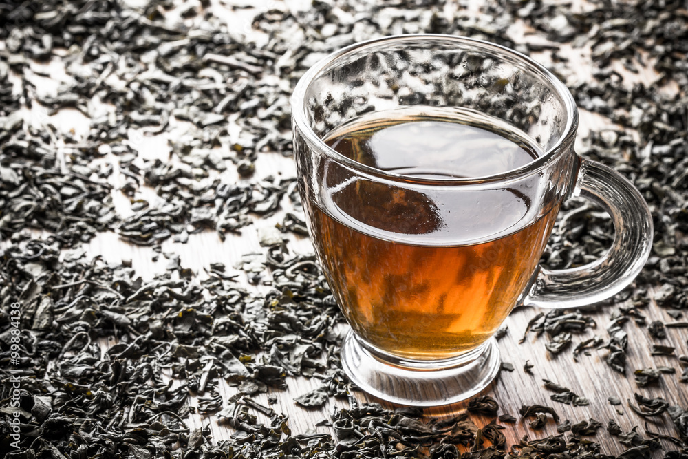 Fototapeta premium Green tea in transparent mug on wooden table with shallow depth of field.