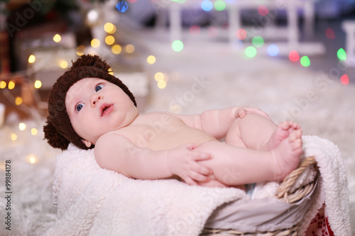 Adorable baby in brown knitted hat in decorated wicker basket