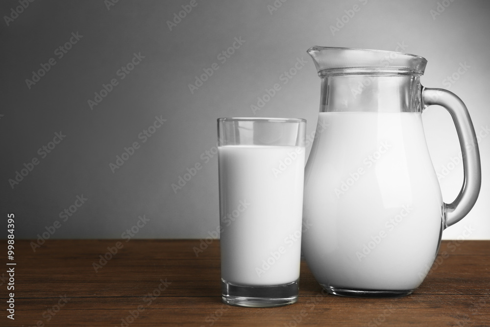Milk in glass and in jar on table on light background Milk in glass and in jar on table on light background