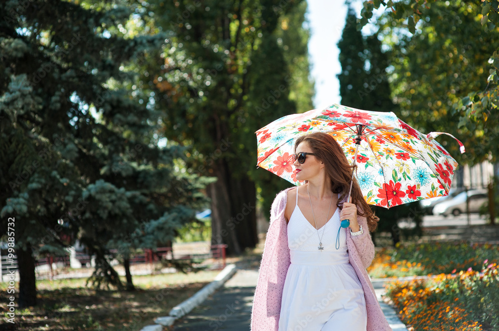 beautiful woman in sunglasses with umbrella walking in the park