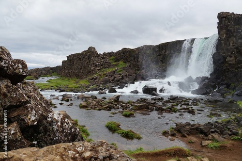 Black lava, green grass and water flowing in Thingvellir near the Althingi in Southwestern Iceland 