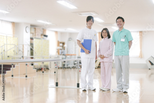 リハビリ室に立つ患者と男性理学療法士と男性看護師