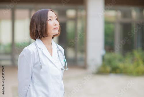 病院の中庭で上を見上げる女性医師 Free Download 病院の中庭で上を見上げる女性医師 - GFXLoad