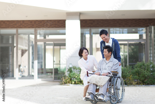 車椅子に座った笑顔の男性患者と男性医療スタッフと女性看護師