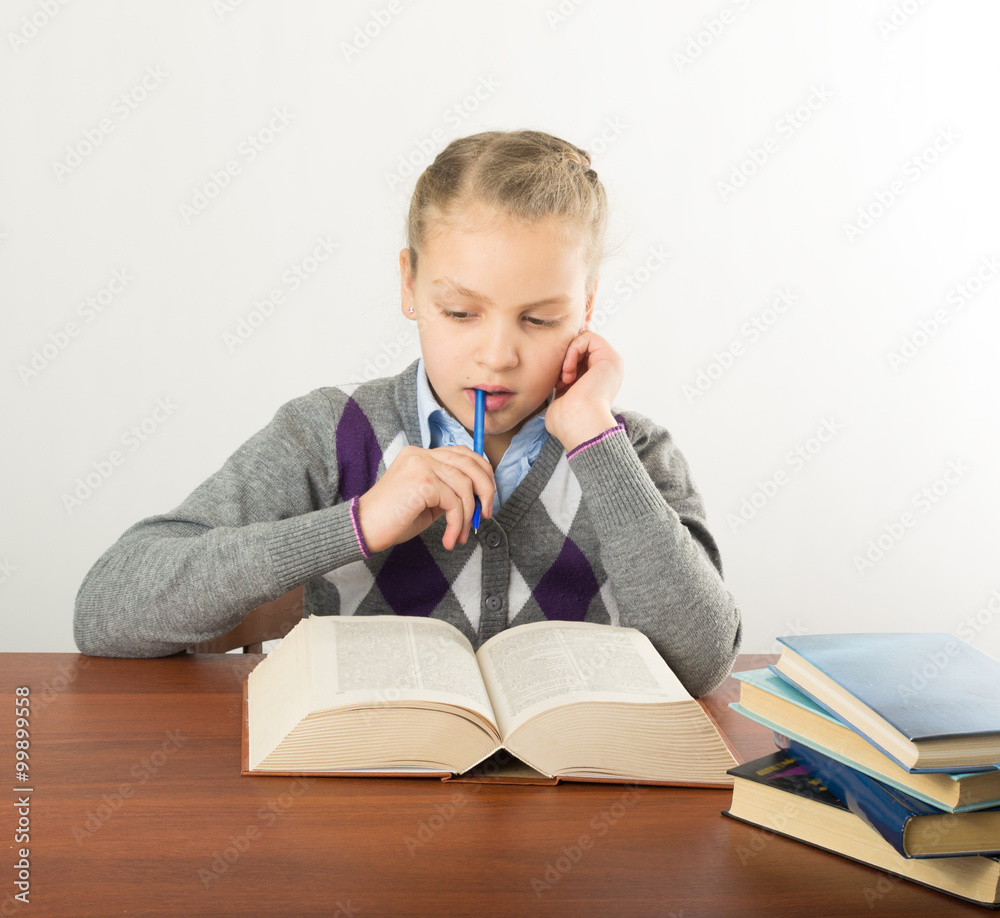 teenager girl sitting at a table in front of her large pile of books. schoolgirl reading a book and doing homework teenager girl sitting at a table in front of her large pile of books. schoolgirl reading a book and doing homework