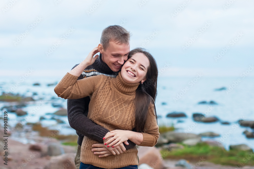 Young couple hugging on a rock on the beach Young couple hugging on a rock on the beach