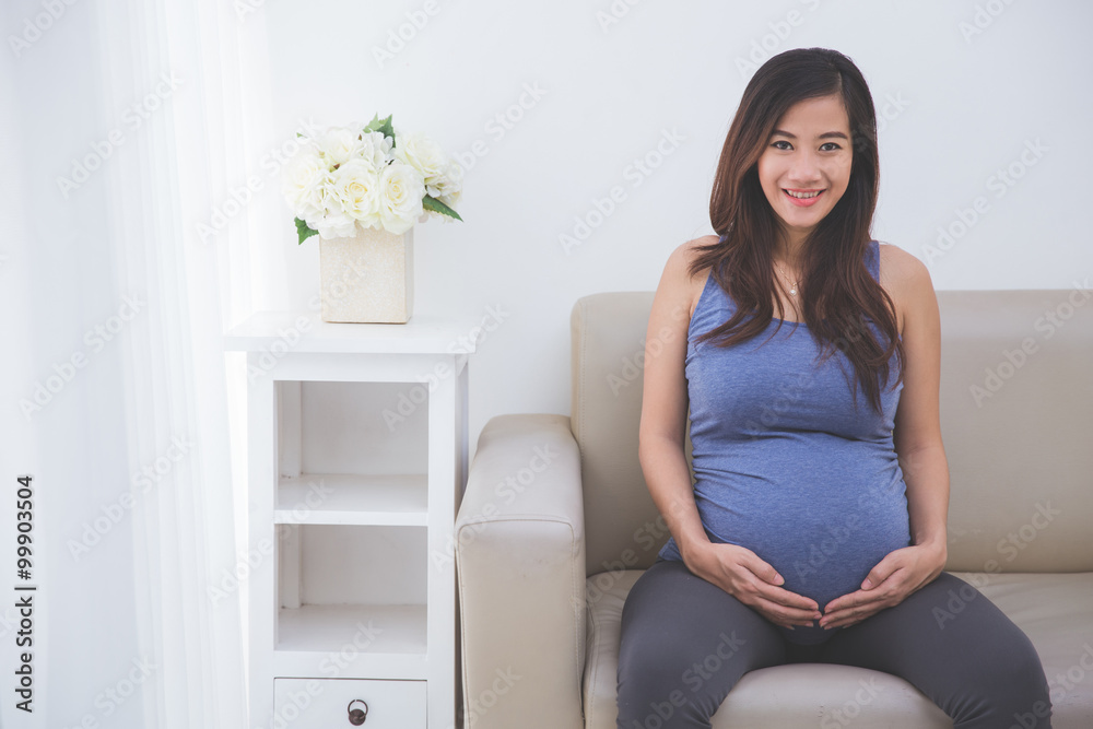 Beautiful pregnant woman smiling in to camera while sitting on t Beautiful pregnant woman smiling in to camera while sitting on t