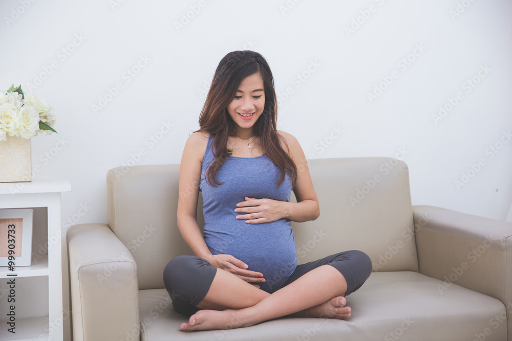 Beautiful pregnant woman smiling in to her belly while sitting o Beautiful pregnant woman smiling in to her belly while sitting o