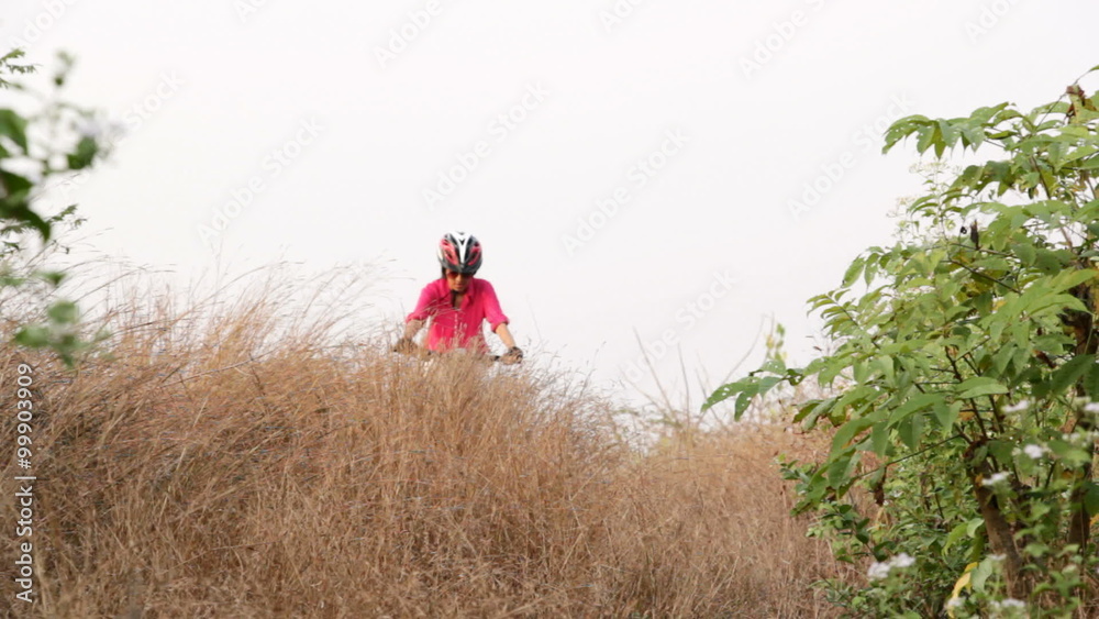 Teen girl cycling downhill while off road biking in forest and hilly terrain Teen girl cycling downhill while off road biking in forest and hilly terrain