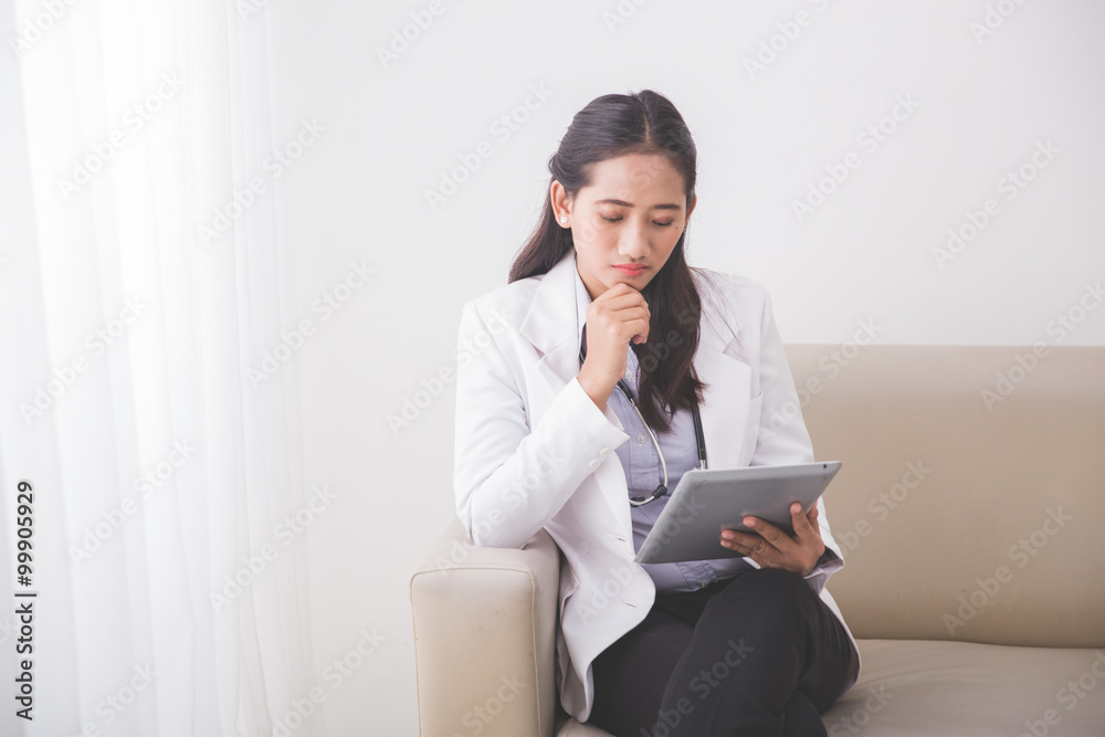 Young asian Female doctor reading something on the tablet pc and Young asian Female doctor reading something on the tablet pc and