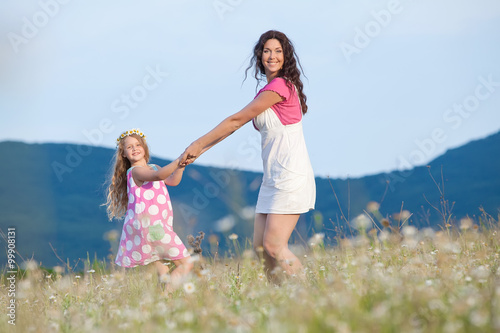 Happy family are resting in a chamomile field