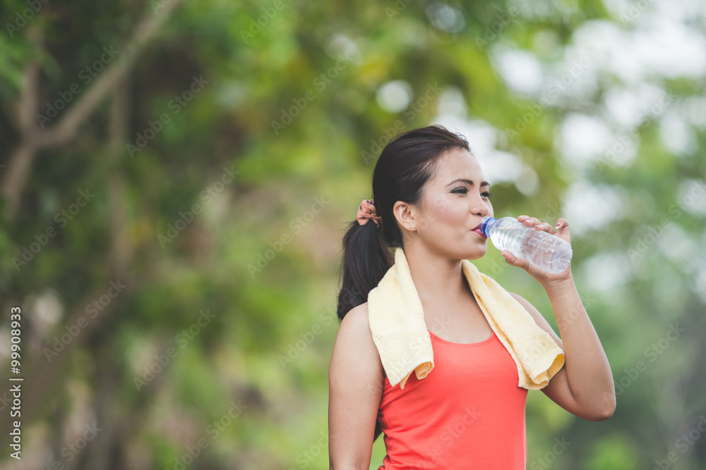 Young asian woman drinking water after doing excercise outdoor i Young asian woman drinking water after doing excercise outdoor i