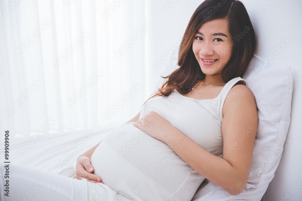 Beautiful pregnant woman smiling in to camera while sitting on t Beautiful pregnant woman smiling in to camera while sitting on t