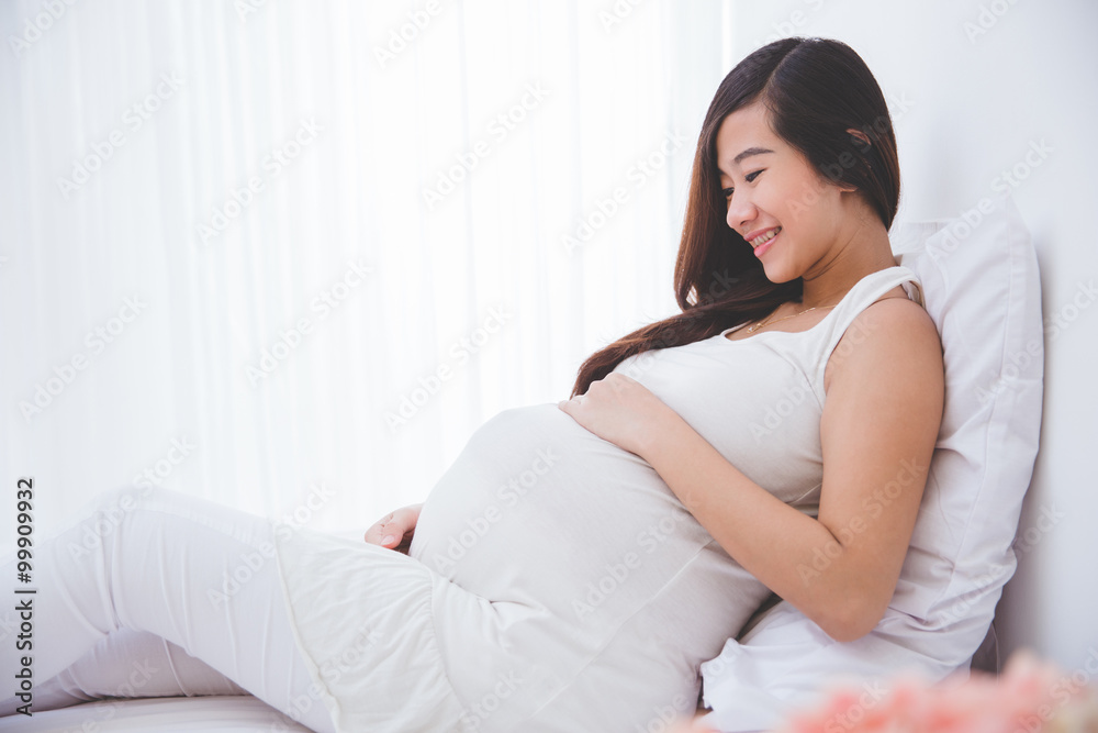 Beautiful pregnant woman smiling looking at her belly Beautiful pregnant woman smiling looking at her belly