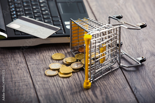Credit card on a laptop, from supermarket trolleys dropped coins photo