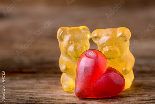 macro two yellow gummy bears with red hearts on wood