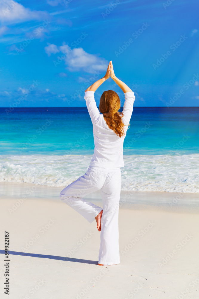 Young woman practices morning exercises on the beach Young woman practices morning exercises on the beach