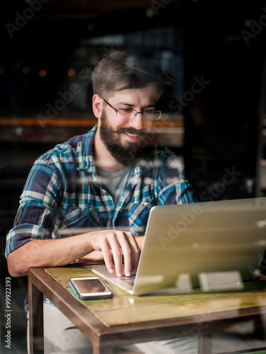 Young man typing on his laptop in coffee shop 