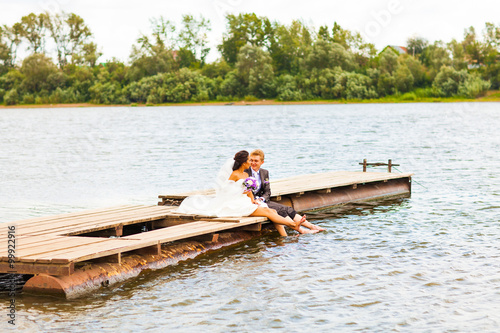 Beautiful bride with groom by a lake. Kiss and hug each other