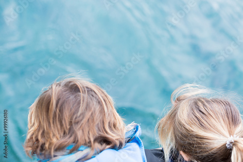Back view of two children looking down at water