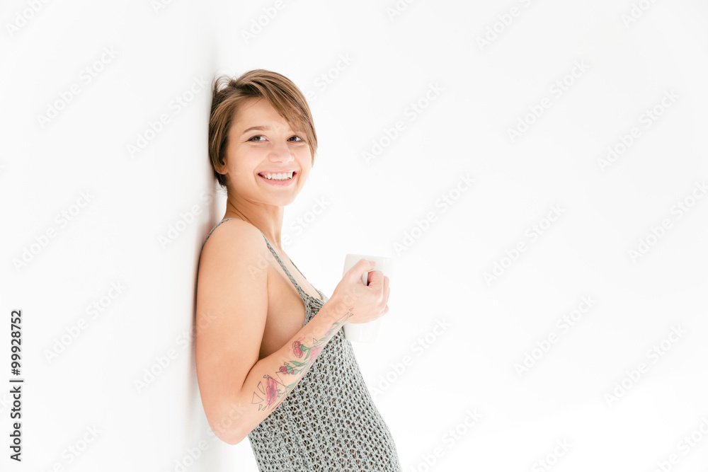 Fototapeta premium Happy cheerful young woman leaning the wall and drinking tea