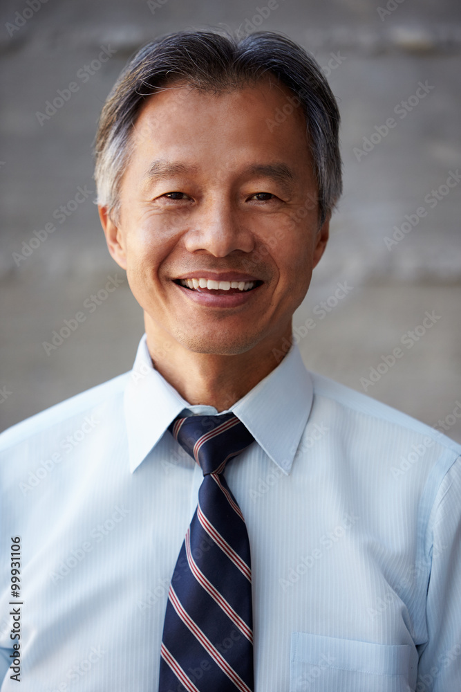 Asian Businessman Standing Against Wall In Modern Office Asian Businessman Standing Against Wall In Modern Office