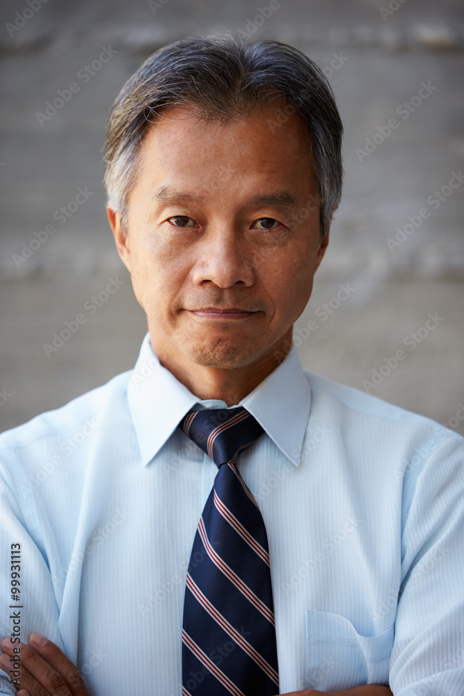 Asian Businessman Standing Against Wall In Modern Office Asian Businessman Standing Against Wall In Modern Office