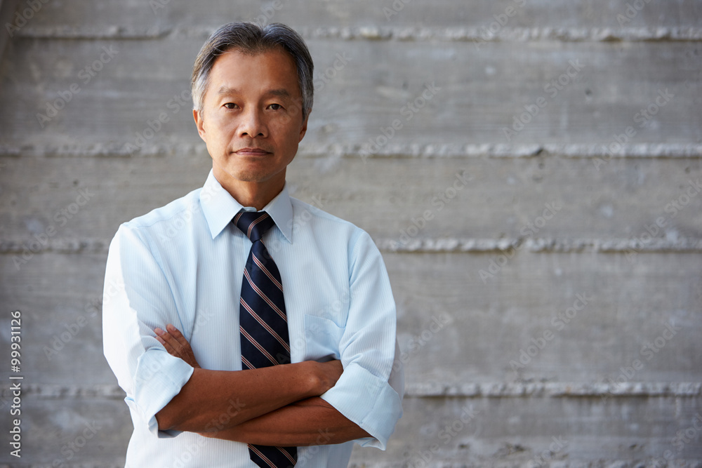 Asian Businessman Standing Against Wall In Modern Office Asian Businessman Standing Against Wall In Modern Office